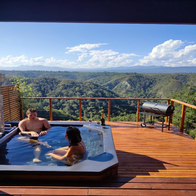 two people sitting in a hot tub on a deck at Cliffhanger Cottages in Rheenendal