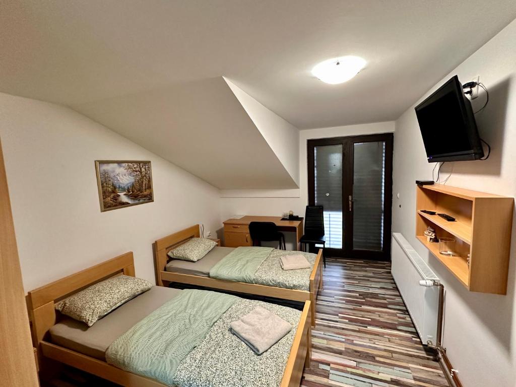 two beds in a room with a tv and a desk at Prenoćište Šoderica in Legrad
