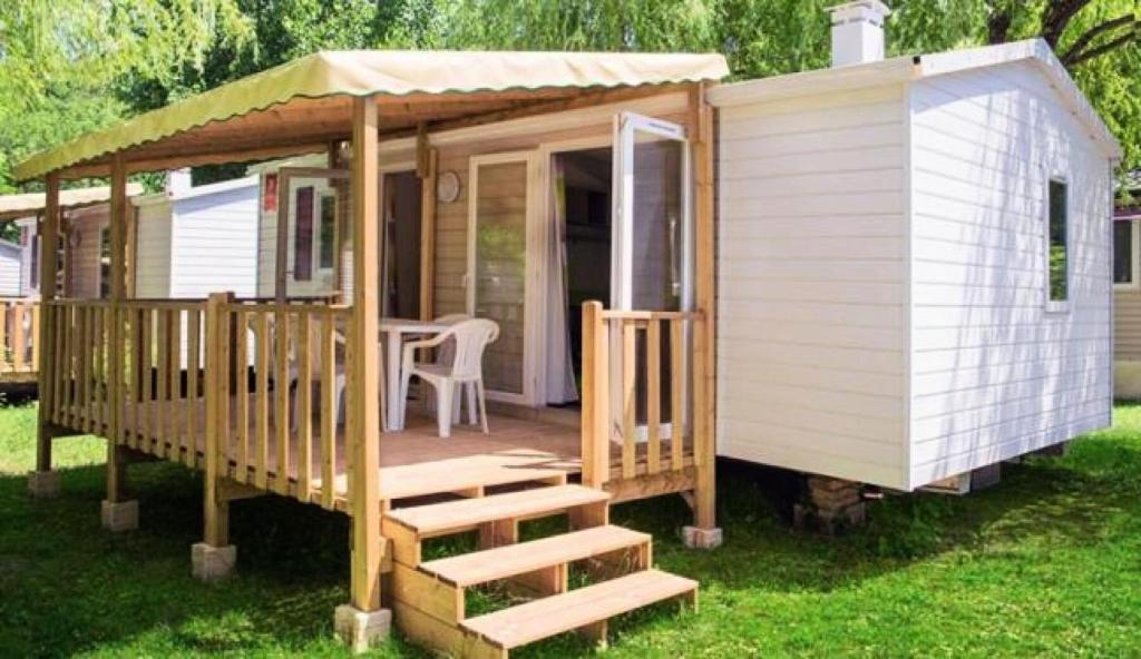 a small white house with a porch and a table at Camping le Lizot - Mobil home 3 pièces 4/6 personnes + TV MAE-8684 in Saint-Mandé-sur-Brédoire