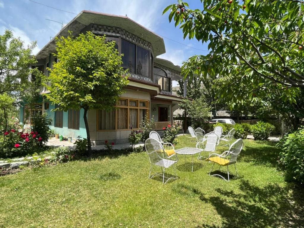 a yard with chairs and a table in front of a house at Pacific Guest House Skardu in Skardu