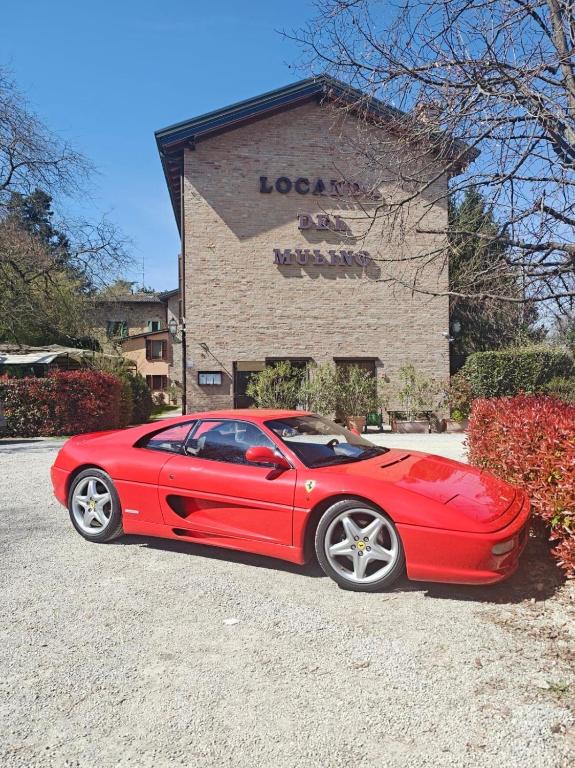 a red car parked in front of a building at Locanda Del Mulino in Maranello
