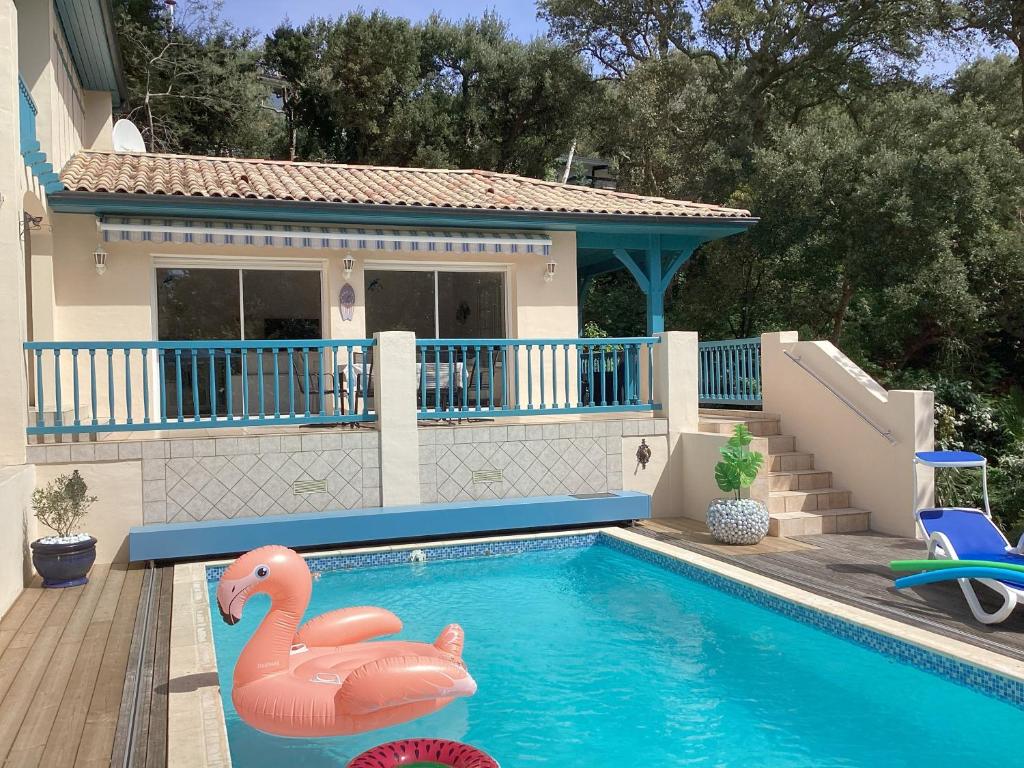 a pool with two inflatable flamingos in front of a house at Villa Rose in Seignosse