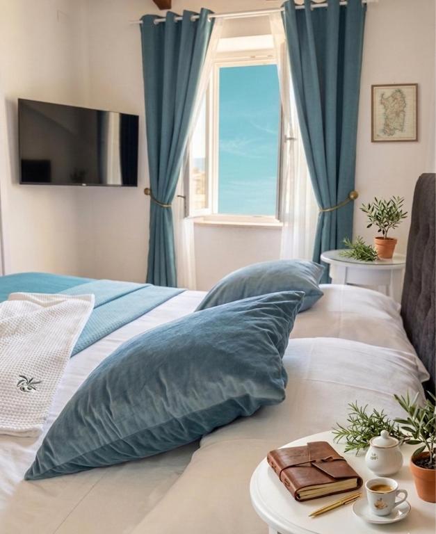 a bedroom with a bed with pillows and a window at Jacaranda Rooms in SantʼAntìoco