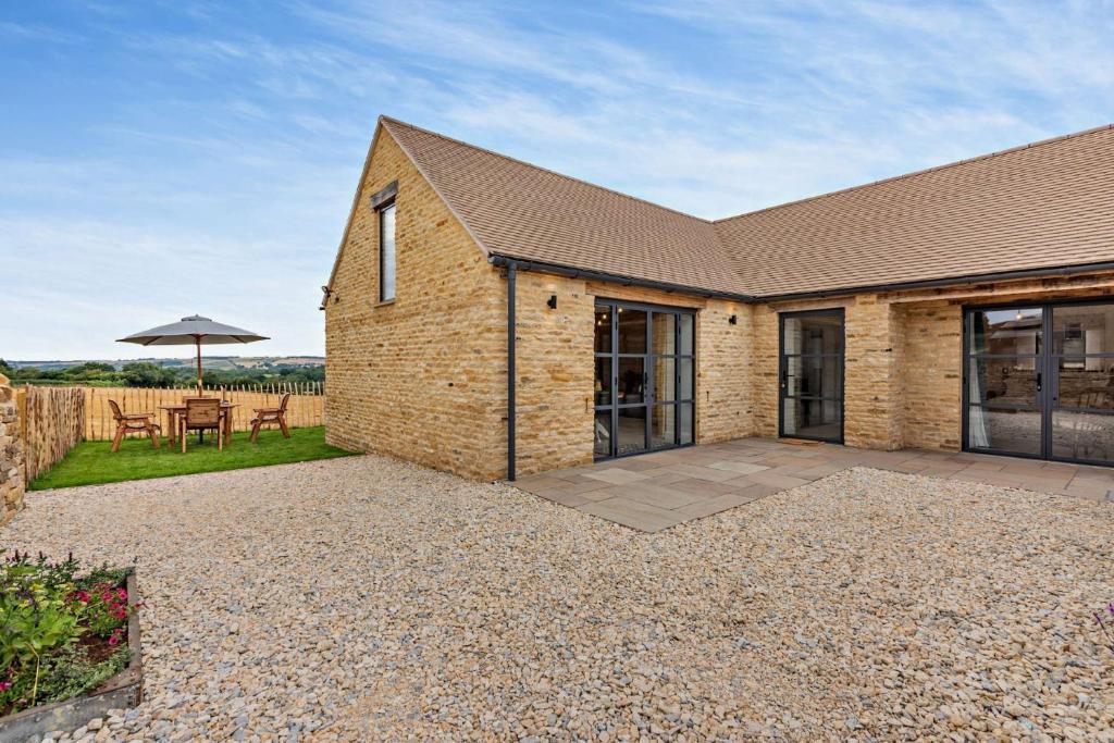 a brick house with a patio and an umbrella at Fox in Charlbury
