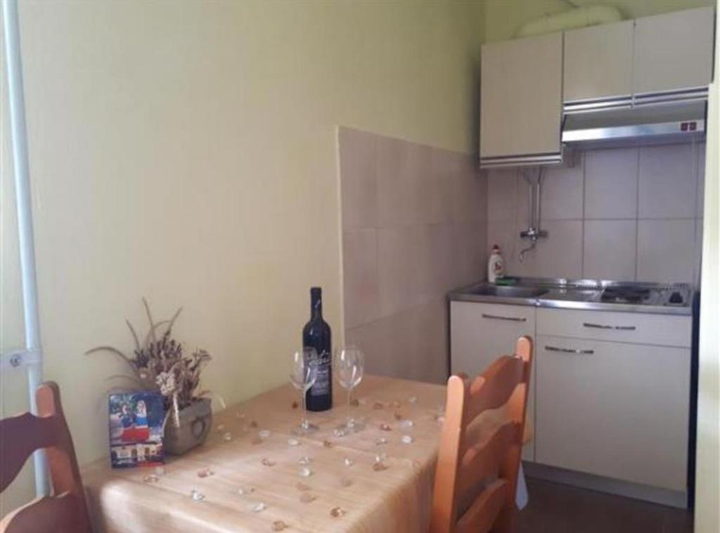 a kitchen with a table with a bottle of wine on it at Apartmani Borić in Orebić