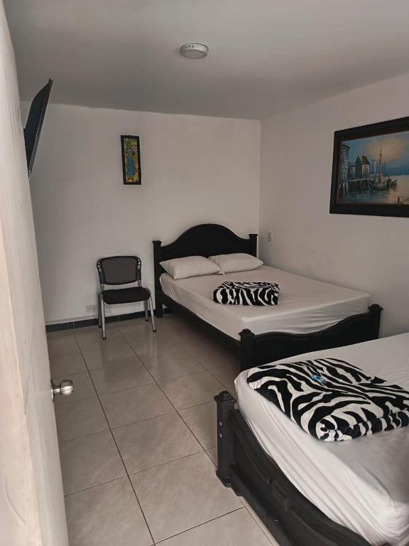 a room with two beds and a chair in it at Hotel Confort Boutique in Rionegro