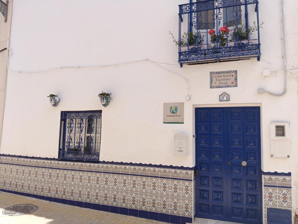 a white building with a blue door and a balcony at casa rural excentrico alcala in Vélez de Benaudalla