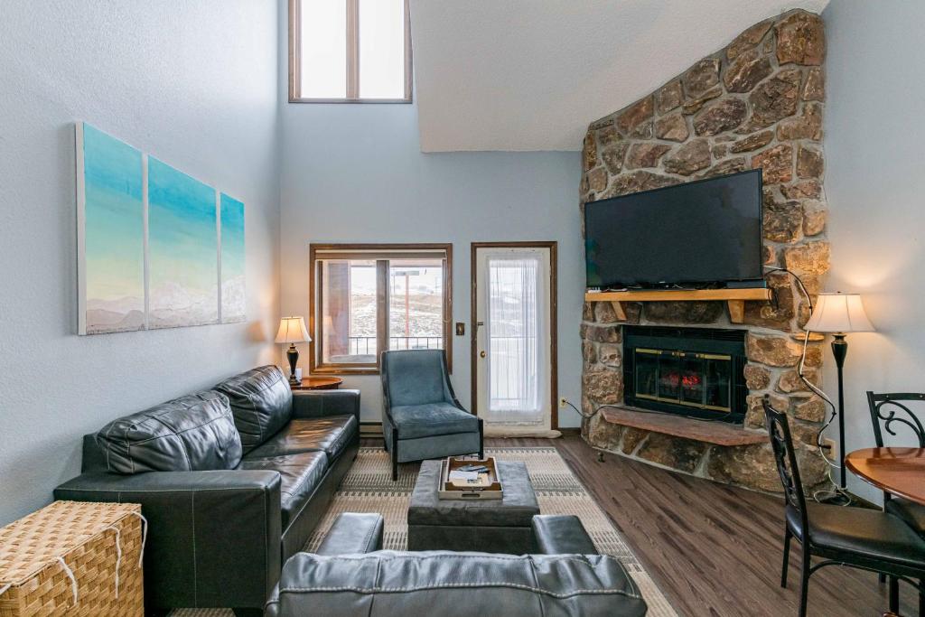 a living room with a couch and a stone fireplace at 643 Silvercreek Inn Condo in Granby