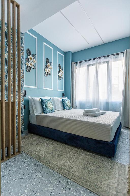 a bedroom with a large bed with blue walls at Ernest Suites Psiri in Athens