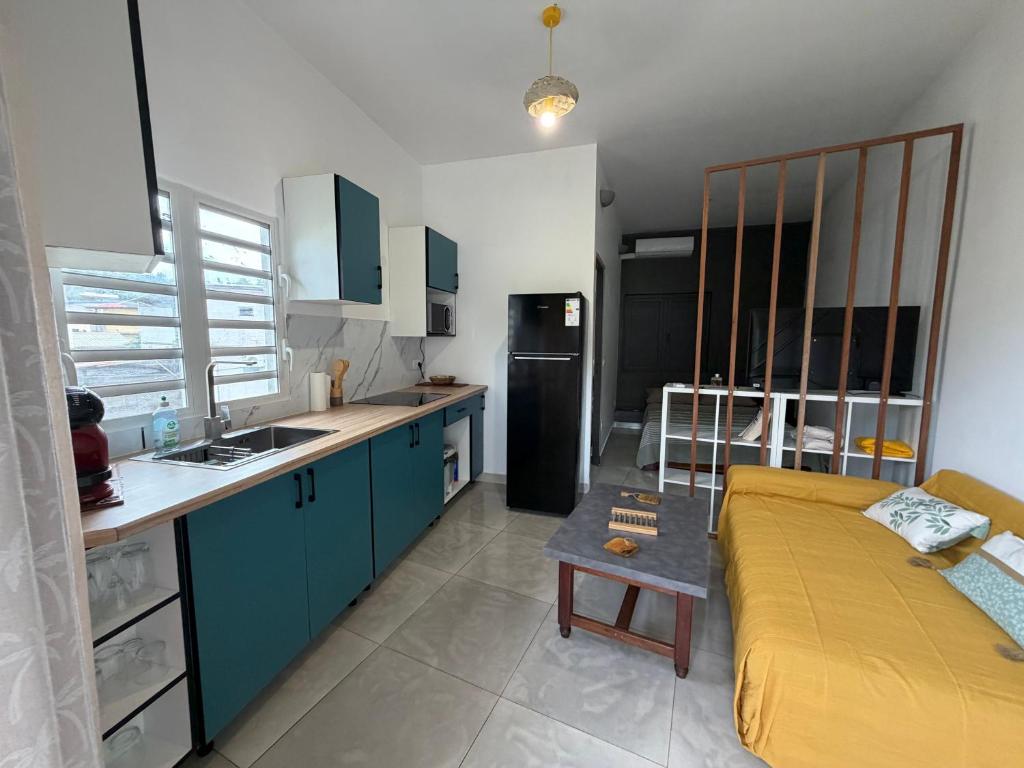 a kitchen with blue cabinets and a yellow bed in it at Le manga in Chiconi