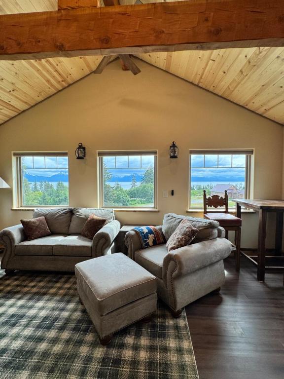 a living room with couches and a table and windows at Rustic Bay View Cabins- Lodge in Homer
