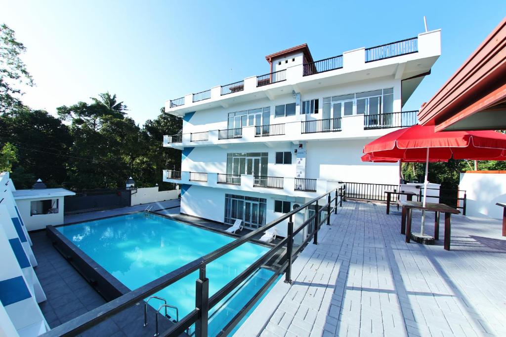 a hotel with a swimming pool and a building at Hotel Emerald Green in Weligama
