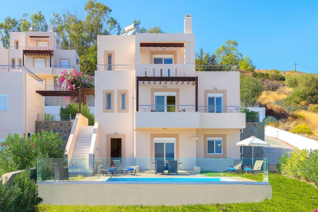 a white house with a blue roof and white walls at Athoniki Villas in Kalathos