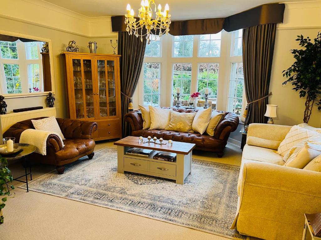 a living room with leather furniture and a chandelier at The Old Rectory Chicklade in Chicklade