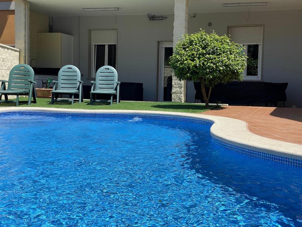 a blue swimming pool with chairs next to a house at Apartamento Río Bispo in Bueu