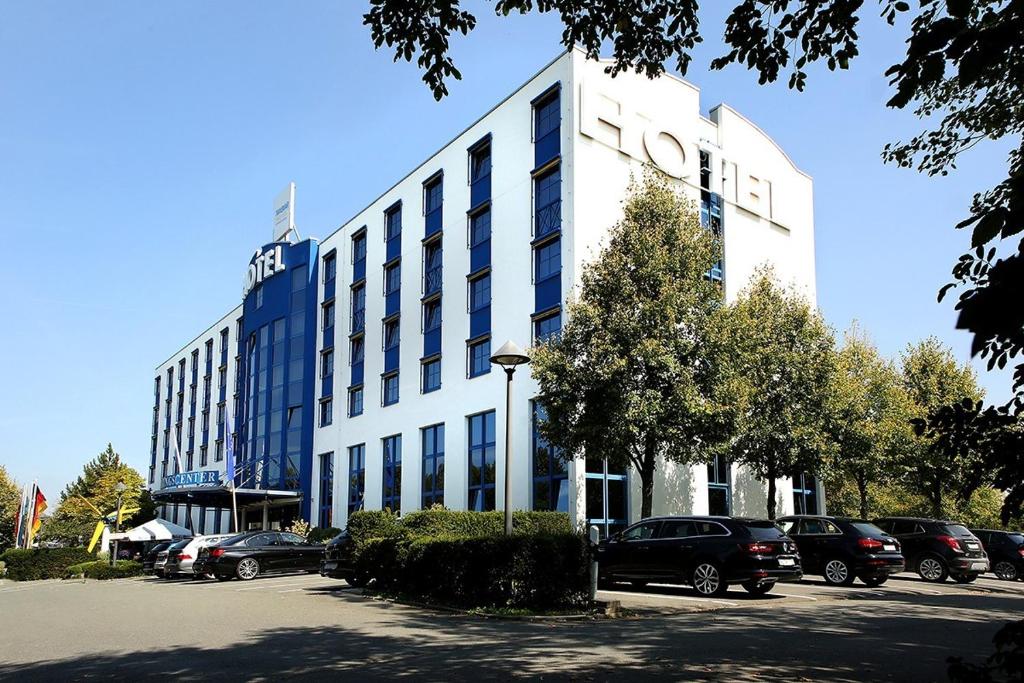 a large white building with cars parked in a parking lot at Transmar Travel Hotel in Bindlach