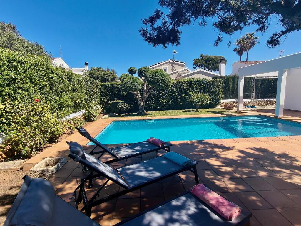 a swimming pool with two chairs next to a house at VILLA SAVINA in Cala en Blanes