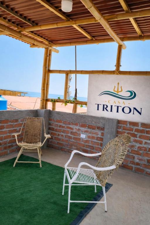 two wicker chairs sitting in front of a sign at Casa de Playa Triton in Máncora