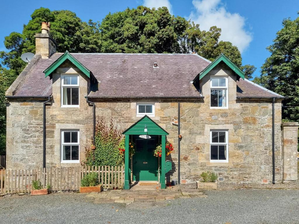 an old stone house with a green door at The Coach House in Girvan