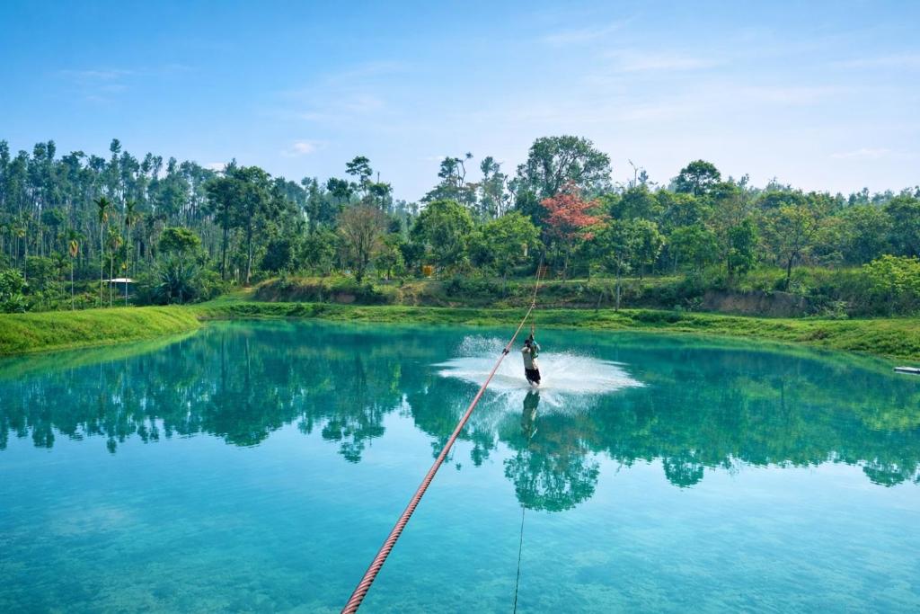 a man is water skiing on a lake at CoffeeINN Homestay - Water Activities, Jeep Ride, Home Food in Sakleshpur