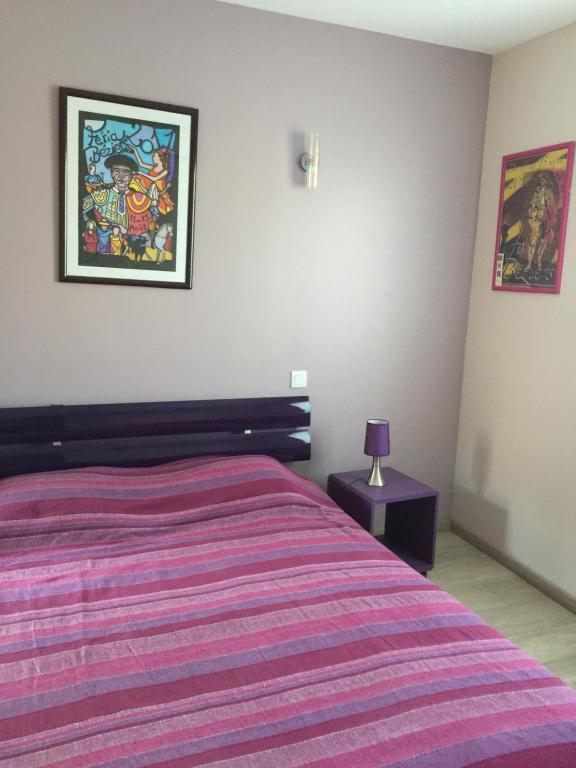 a bedroom with a bed with a purple striped blanket at Delaporte in Béziers