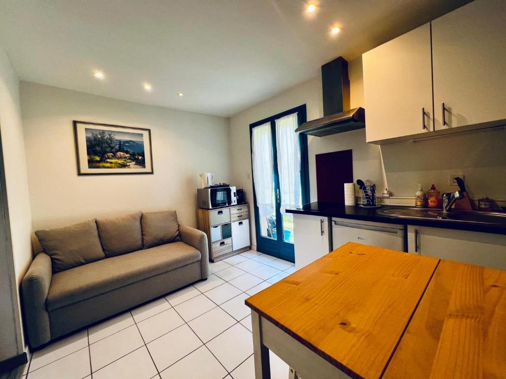 a kitchen and living room with a couch and a table at Petite maison Cosy Le gaucher in Muret