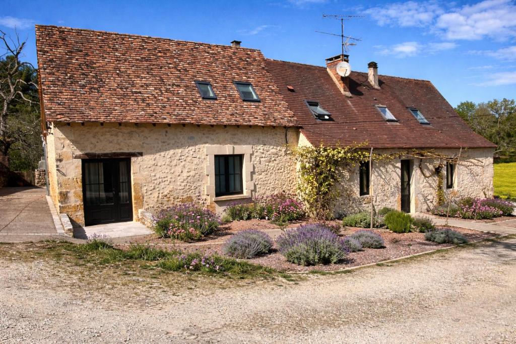 an old stone house with flowers in front of it at La bergerie des petits loups in Montagnac-la-Crempse