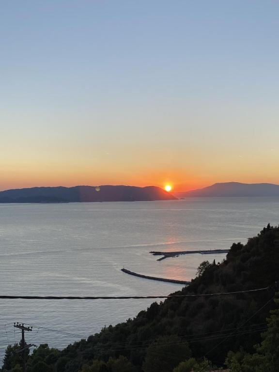 a sunset over a body of water with trees at Aegean Panorama in Klíma