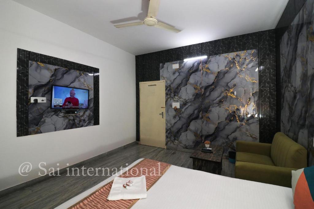 a room with a tv on the wall and a couch at Sai International Guest House in kolkata