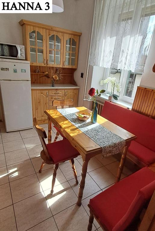 a kitchen with a wooden table and red chairs at Hanna 3 Apartman in Kőszeg