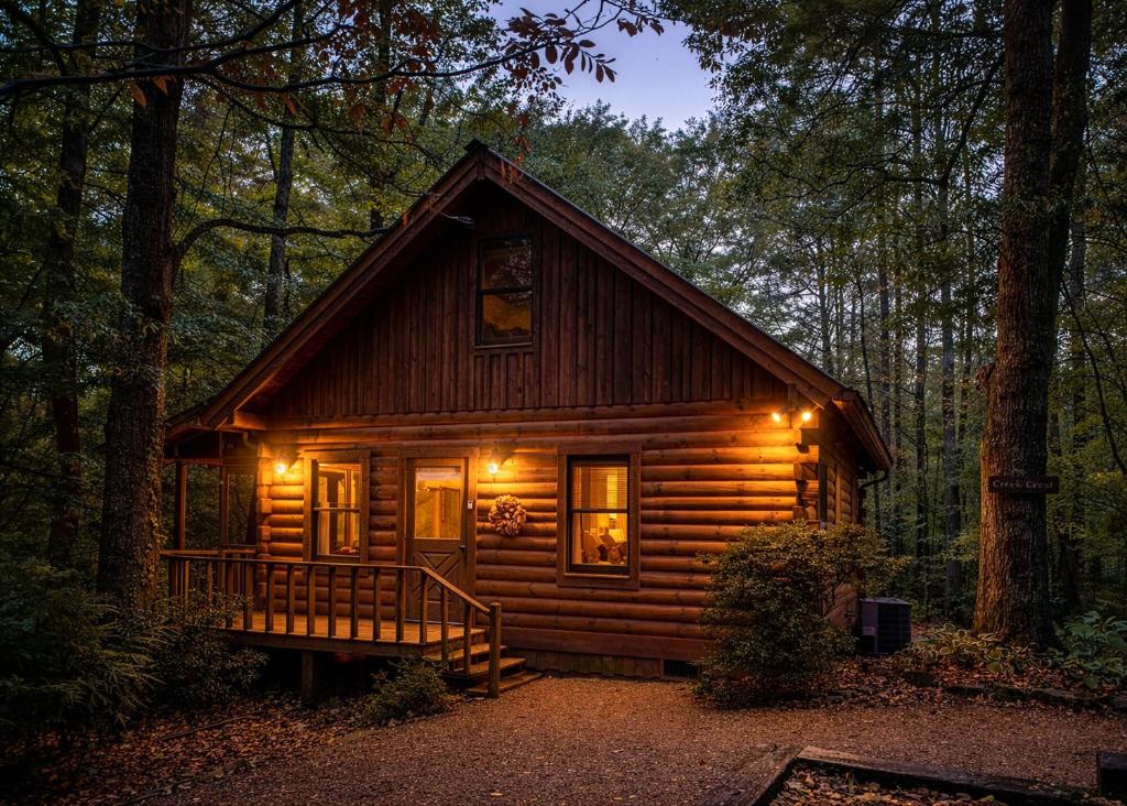 a log cabin in the woods with lights on at Creek Crest Cabin Ocoee Riverside Cabin in Ocoee