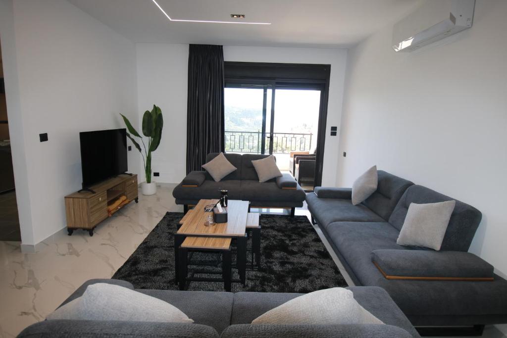 a living room with two couches and a tv at دار المكارم للشقق الفندقية الفاخره in Jerash