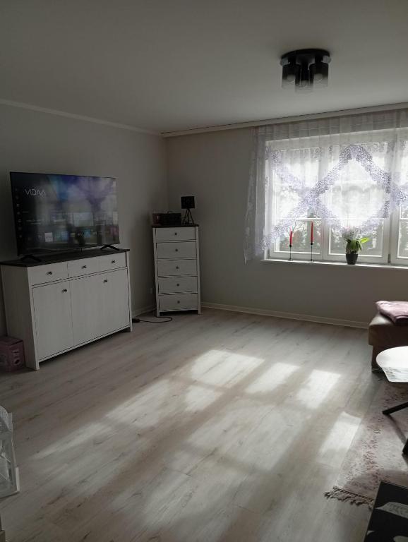 an empty living room with a television and a window at Ferienwohnung am Waldrand 1 in Stary Przybsław