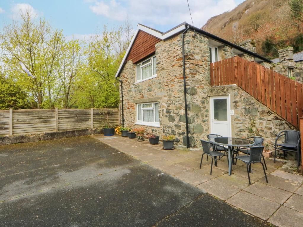 a stone house with a table and chairs in front of it at First Floor Apartment in Porthmadog