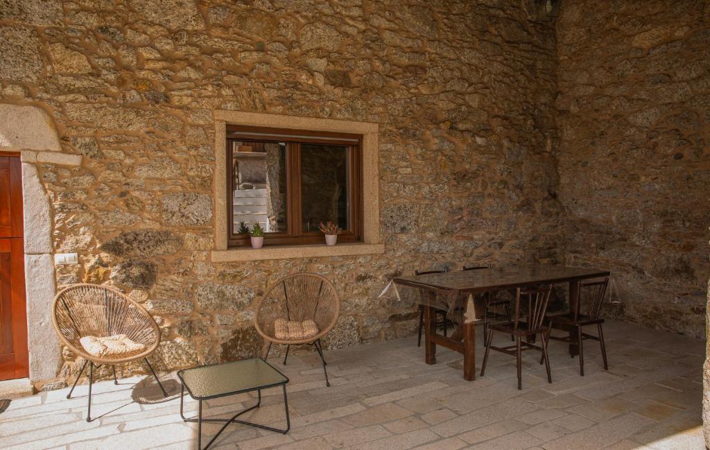 a table and chairs in a stone room with a window at O rincón de Agrón in Melide