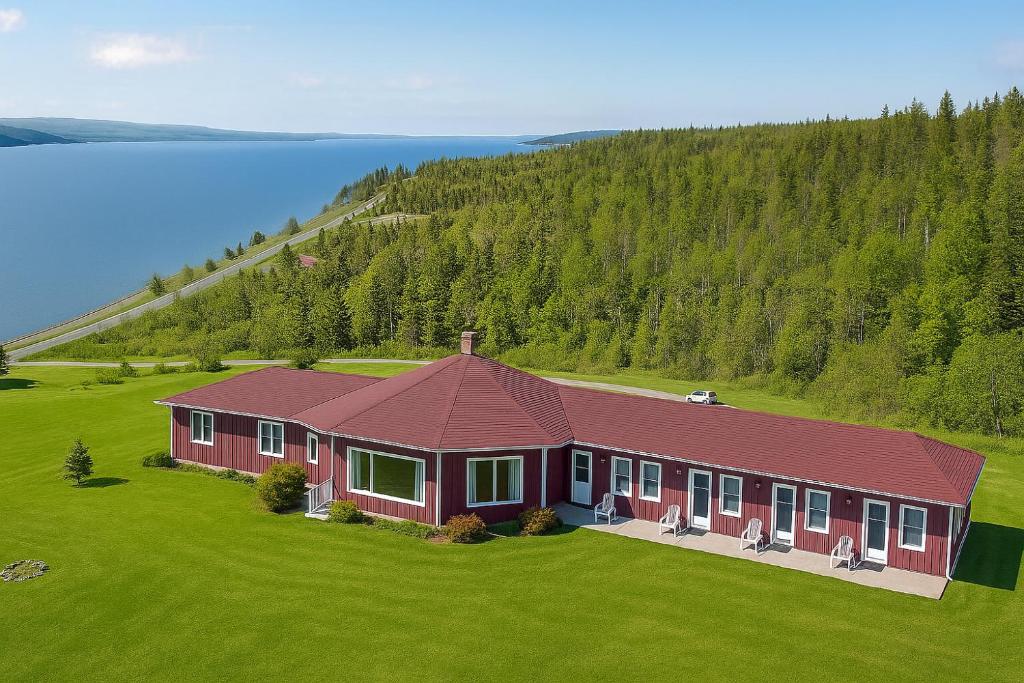 a large red house on a green field with trees at Baddeck Inn in Baddeck