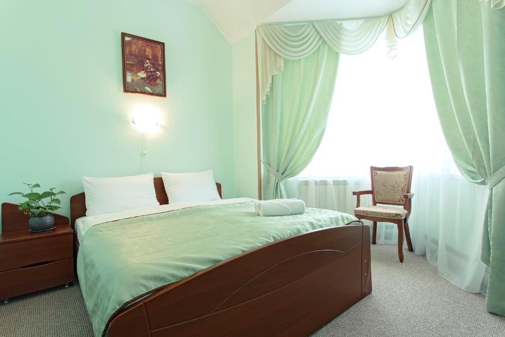 a bedroom with a bed and a chair and a window at Continental Hotel in Rostov on Don