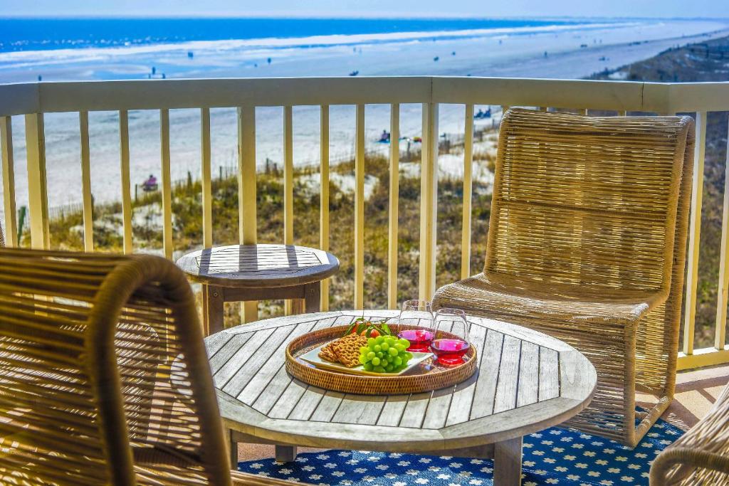 a table with a bowl of fruit on a balcony with the beach at Sunshine Daydream in Folly Beach