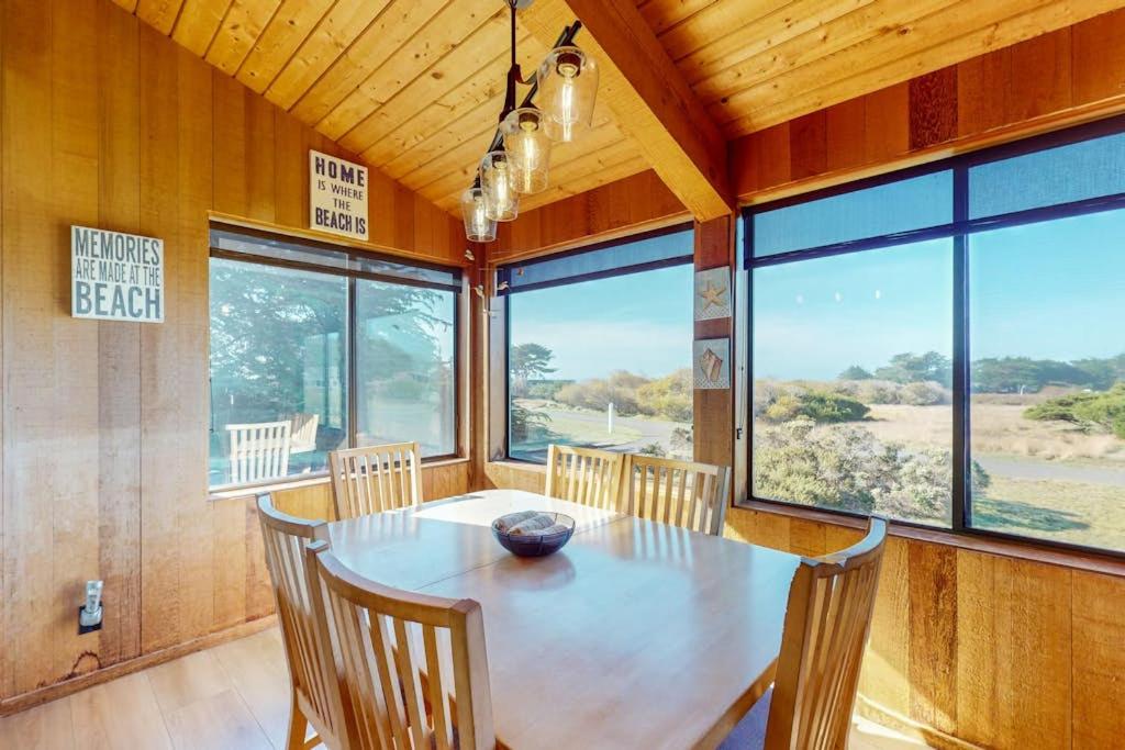 a dining room with a table and chairs and windows at Prentiss Retreat in Sea Ranch