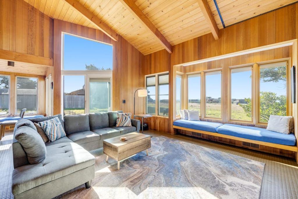 a living room with a couch and a table and windows at Samson Getaway in Sea Ranch