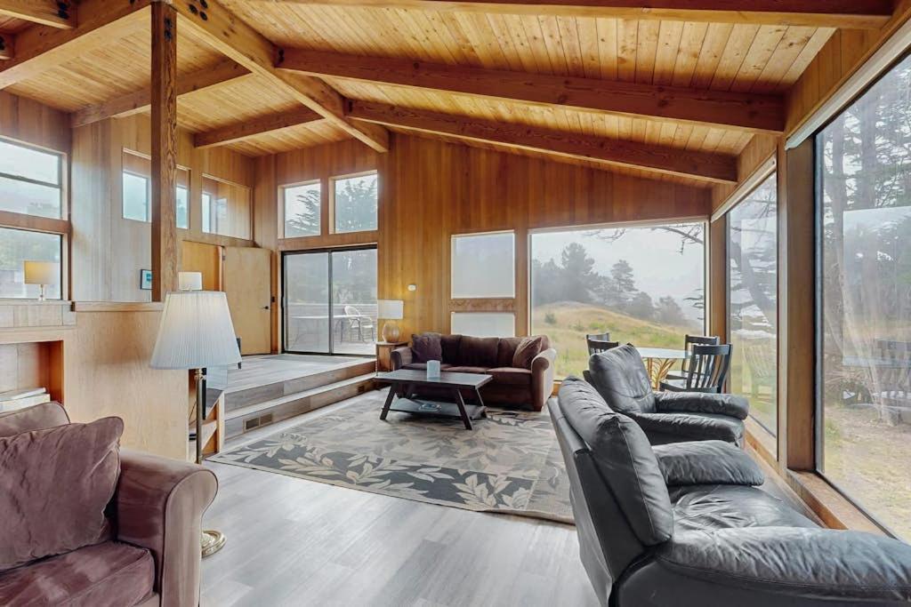 a living room with couches and a table and windows at Stoney House in Sea Ranch