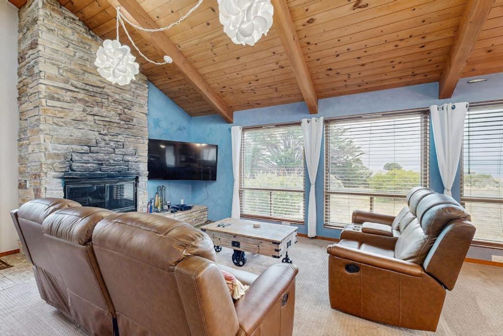 a living room with leather furniture and a stone fireplace at Ocean Star in Sea Ranch