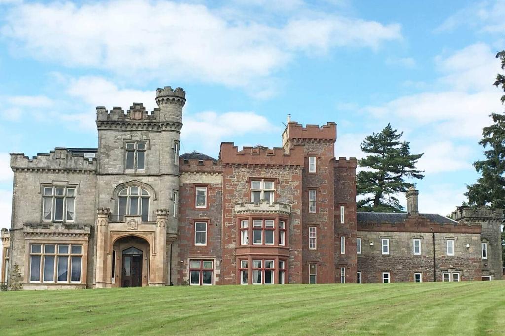 an old castle with a grass field in front of it at The Manor House, Killearn in Killearn