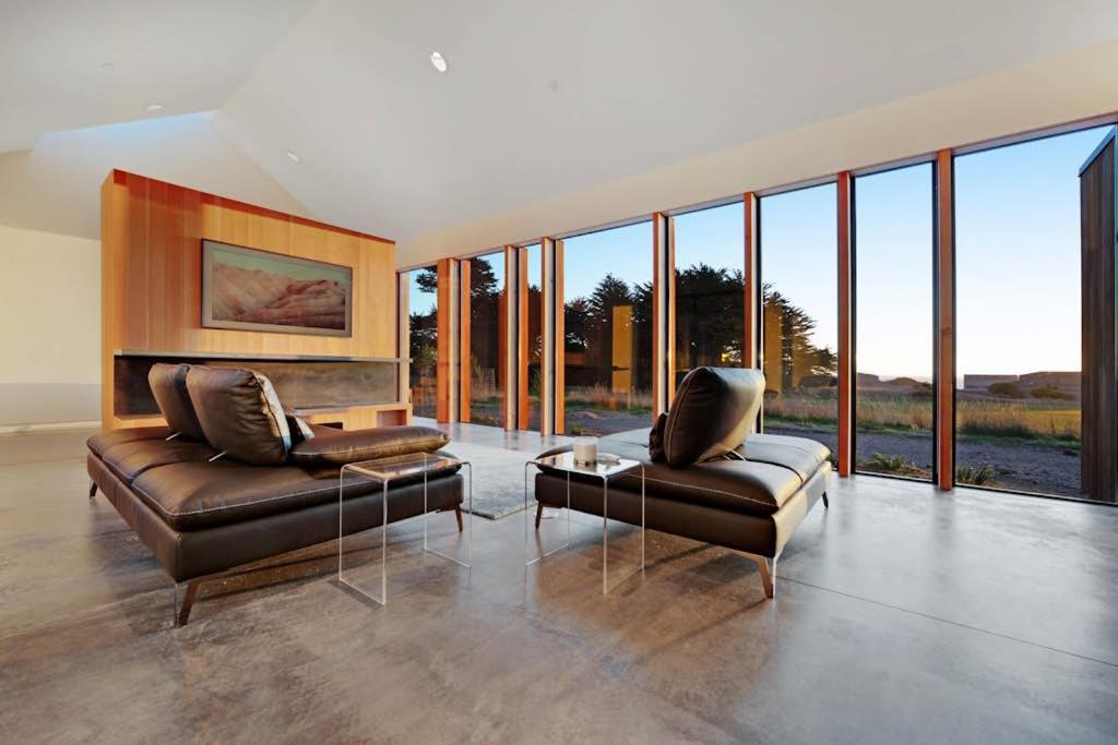 a living room with two leather couches and glass windows at Sky Fall in Sea Ranch