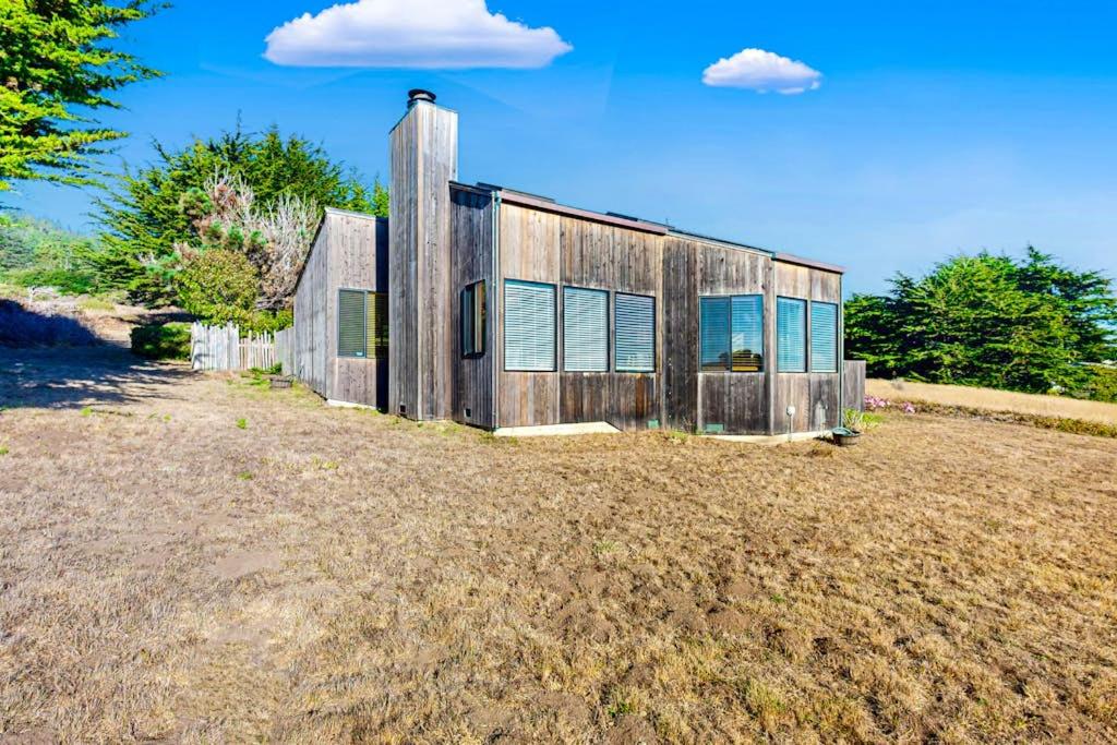 a wooden house sitting on top of a field at Clemons' Cottage in Sea Ranch