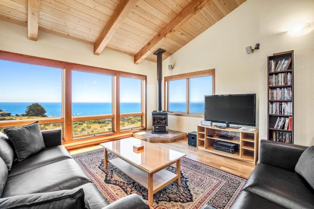 a living room with a couch and a tv and windows at Ascona House in Sea Ranch