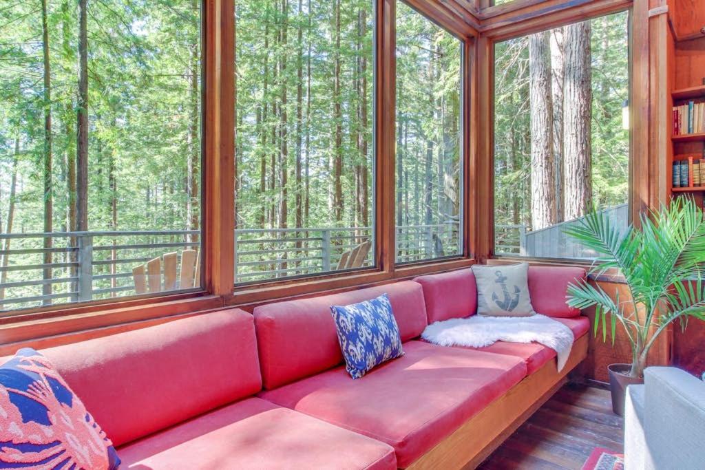 a red couch sitting in a room with windows at The Redwood House in Fish Rock