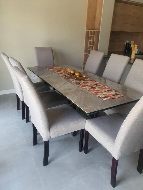 a dining room table with chairs and a table with a bowl on it at Crystal Self Catering 3 bedroom Villa in Swakopmund