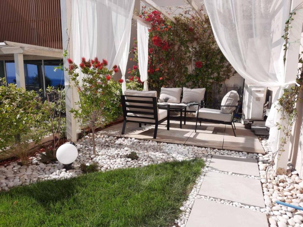 a patio with chairs and a table in a garden at Sea La Sun, Green Coast in Palasë