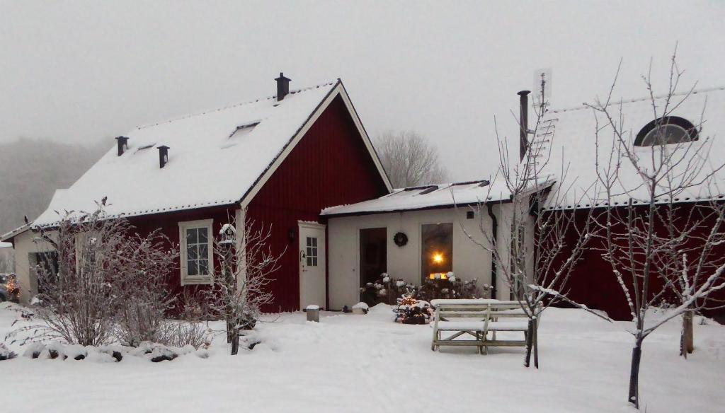 eine rote Scheune im Schnee mit einer Bank in der Unterkunft Huggehus in Förslöv